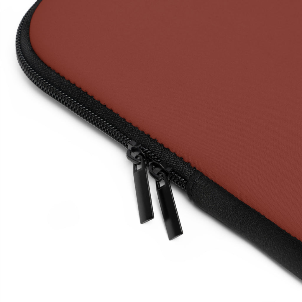 Close-up of black zipper on a  rectangular laptop sleeve in a muted terracotta red color, shown on a plain white background.