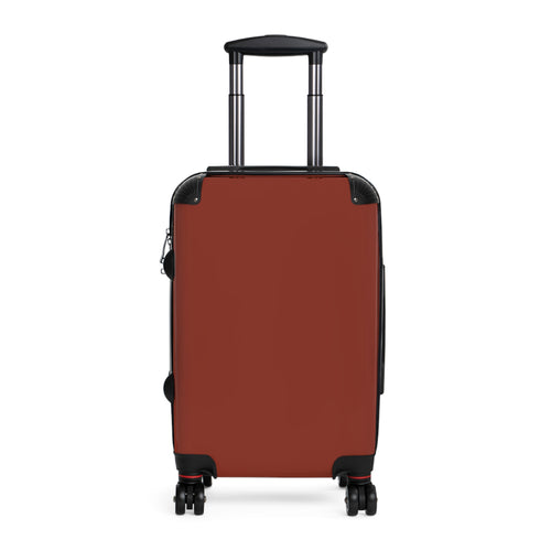 A hard-shell hardside suitcase in a brick red color, featuring a telescoping handle extended upwards and four spinner wheels, shown against a plain white background.