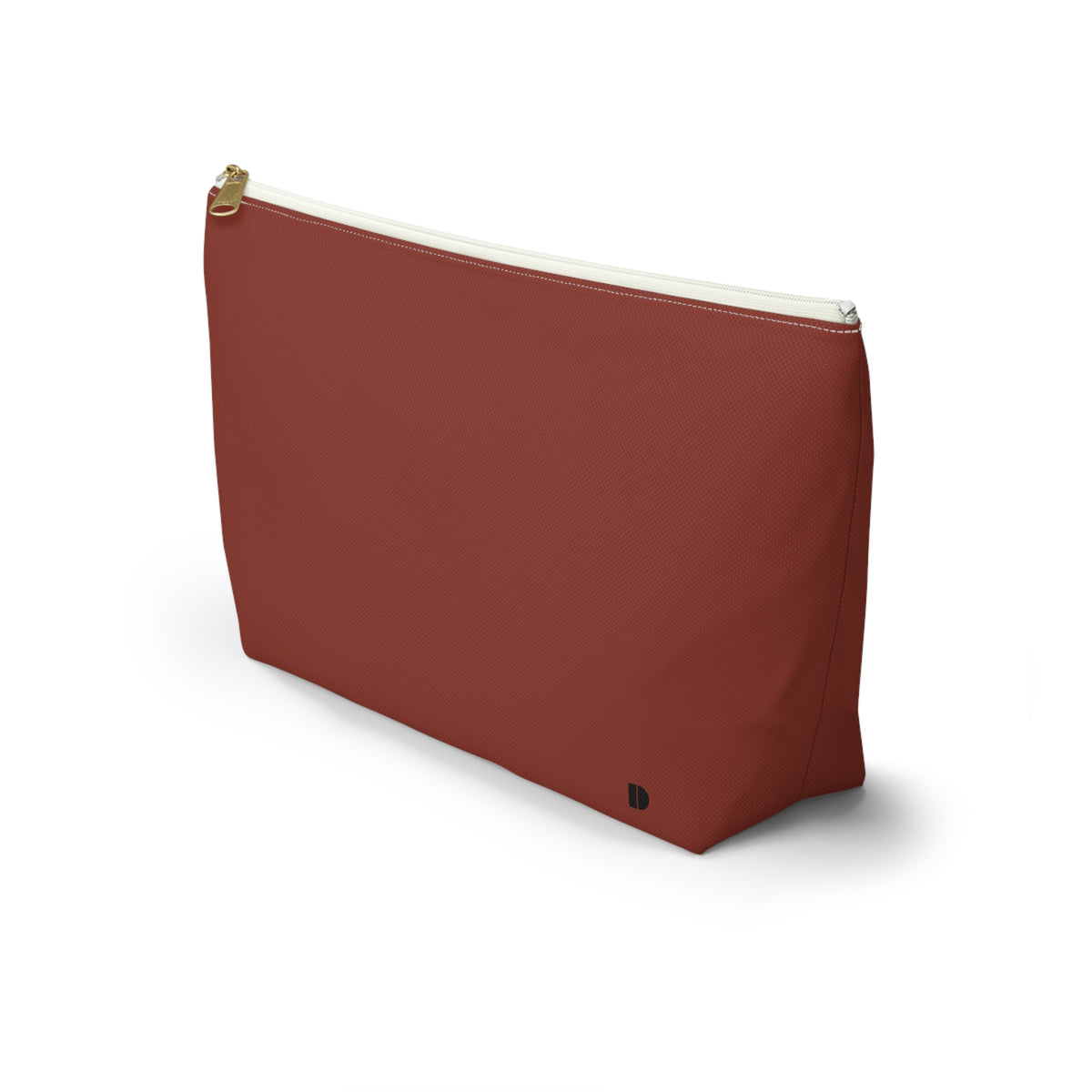 A terracotta red canvas cosmetic pouch with a gold zipper and a small black monogram logo on the bottom right, set against a plain white background.