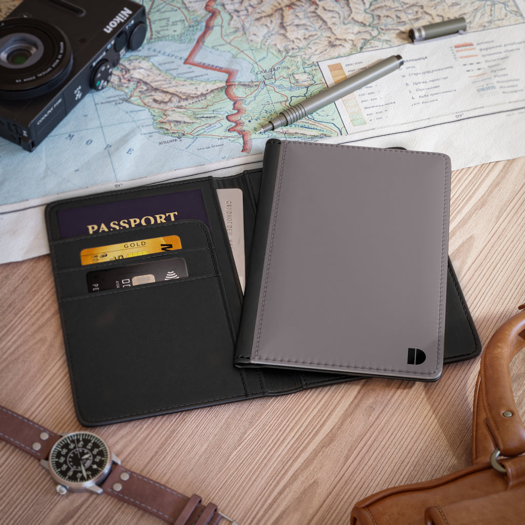 Gray faux leather passport holder with passport and camera on a map