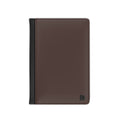 A dark brown faux leather passport cover with a black spine band and a small black monogram logo in the bottom right corner, shown on a plain white background.