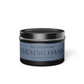 A round metal tin candle with a black lid and base, featuring a dusty blue label that reads 'The Cultivated Desk EVENING OASIS' with citrus, jasmine, and patchouli notes.