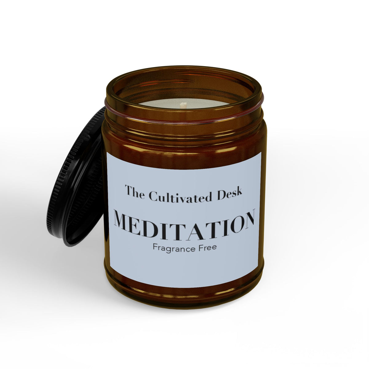 Fragrance-free scented candle in an open 9oz amber glass jar showing the white wax and single wick inside, with the black metal lid leaning against the side, featuring a minimalist light blue label with black serif text reading "The Cultivated Desk," "MEDITATION," and "Fragrance Free." Scented candle titled 'Meditation', available in 9oz and 4oz sizes.