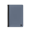 A minimalist card holder or passport cover in a muted slate blue color with a black vertical accent strip on the left edge and a small black monogram logo in the bottom right corner, shown on a plain white background.