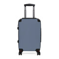 A hard-shell carry-on suitcase in muted blue, featuring an extended telescoping handle and four spinner wheels, shown against a plain white background.