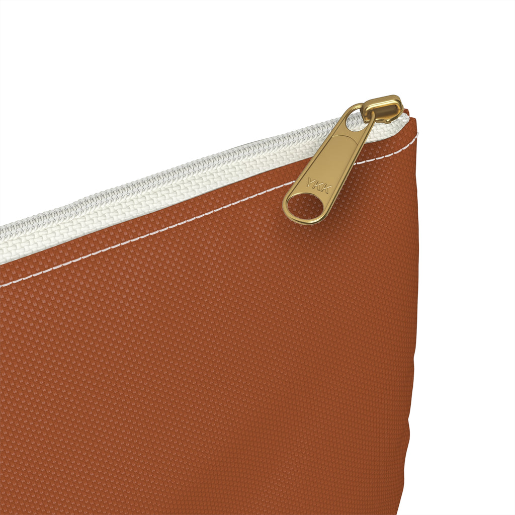 Close-up of a textured rust-colored zippered pouch with a gold-tone metal zipper pull and white zipper tape on a white background.