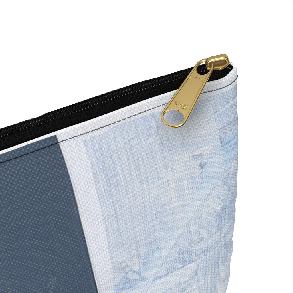 Close-up of a zippered pouch corner showing a black zipper, gold pull tab, and a light blue and white textured print on a white background.