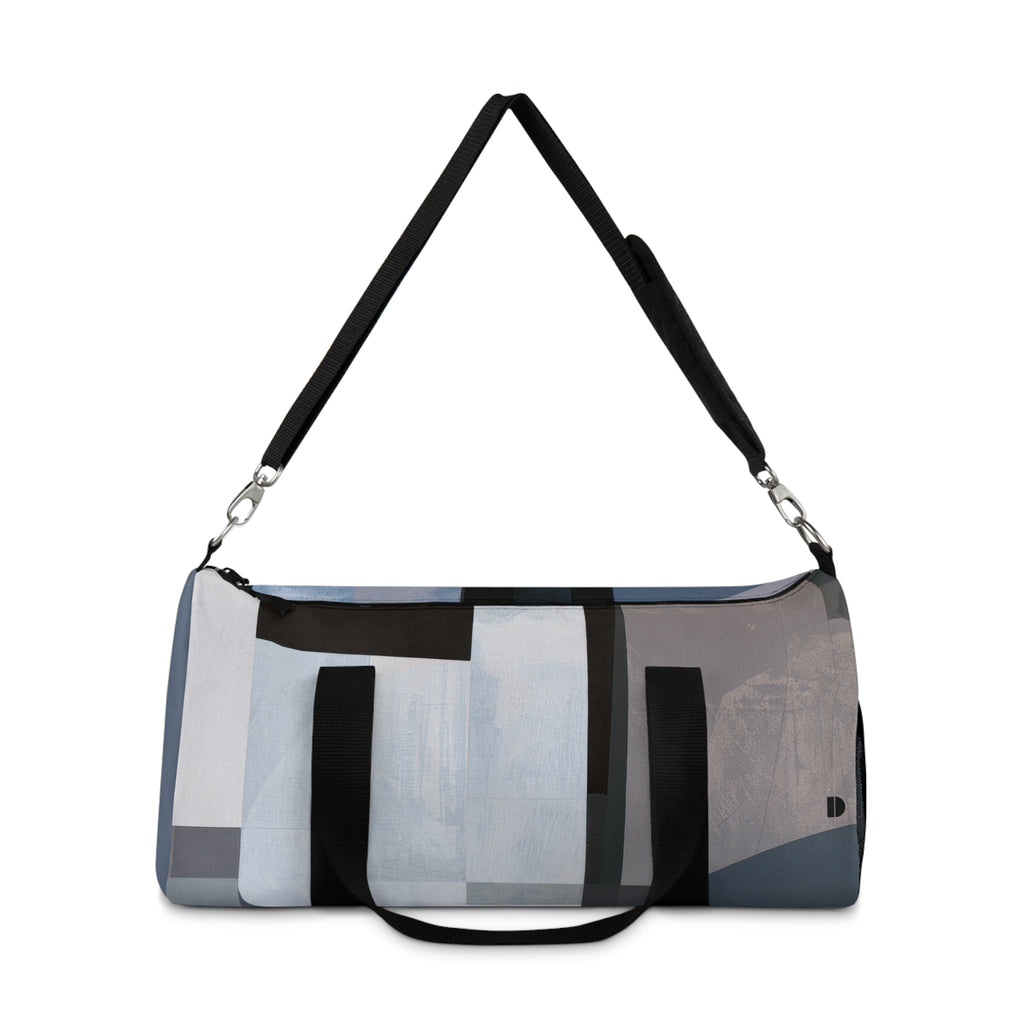 A duffle bag with an abstract geometric pattern in shades of blue, gray, black, and white, featuring a black shoulder strap and a short black handle, shown against a plain white background.