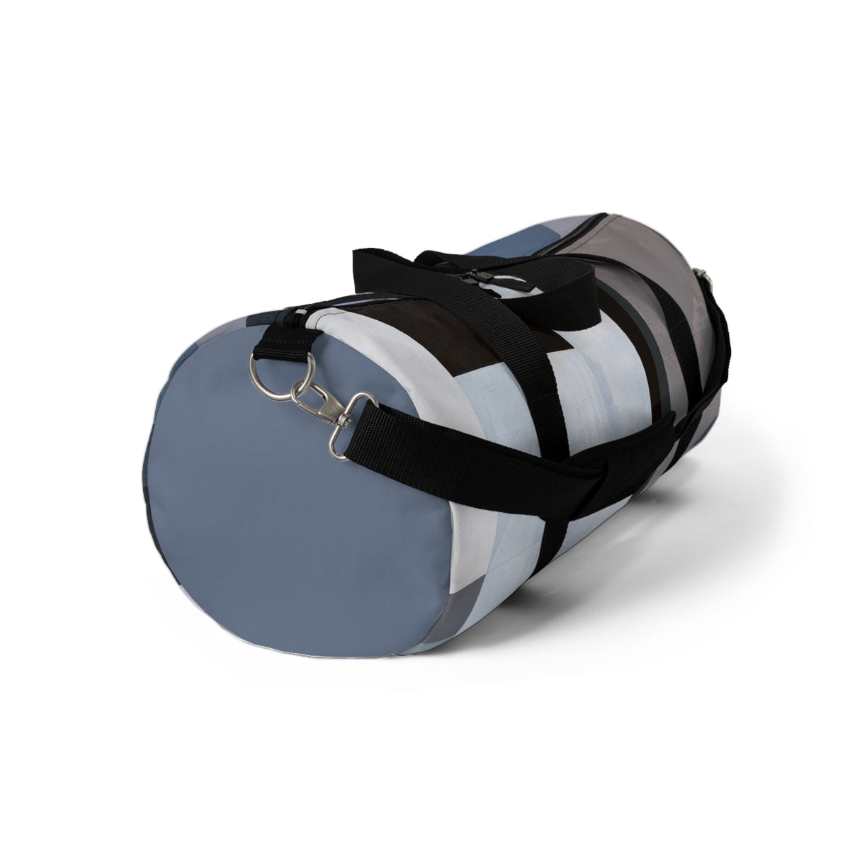 A cylindrical duffel bag with a modern abstract color-blocked pattern in slate blue, white, gray, and black, featuring black carrying handles and a metal D-ring on a white background.