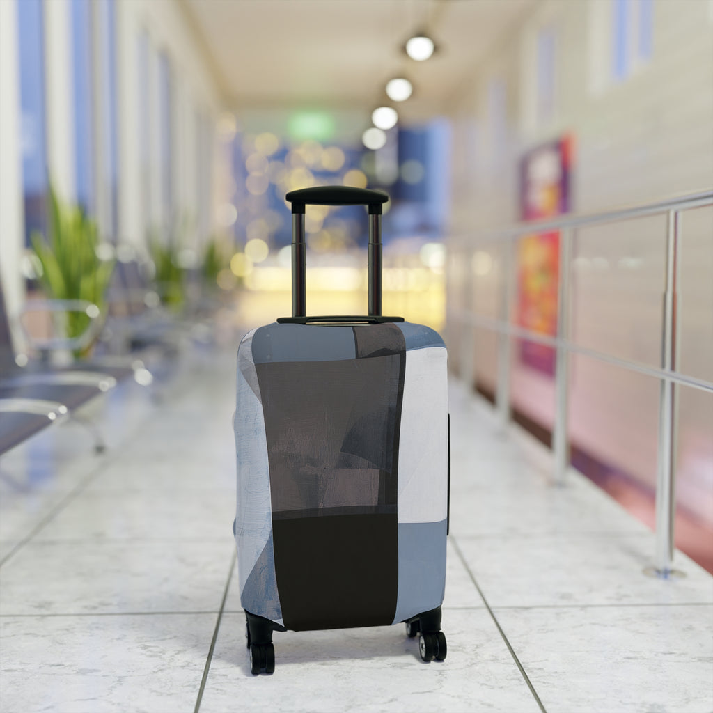 A hard-shell rolling suitcase with an extendable handle and four wheels, covered in a geometric patchwork luggage sleeve in shades of gray, black, and white. The suitcase is positioned in the center of a brightly lit, modern airport terminal corridor with a blurred background.
