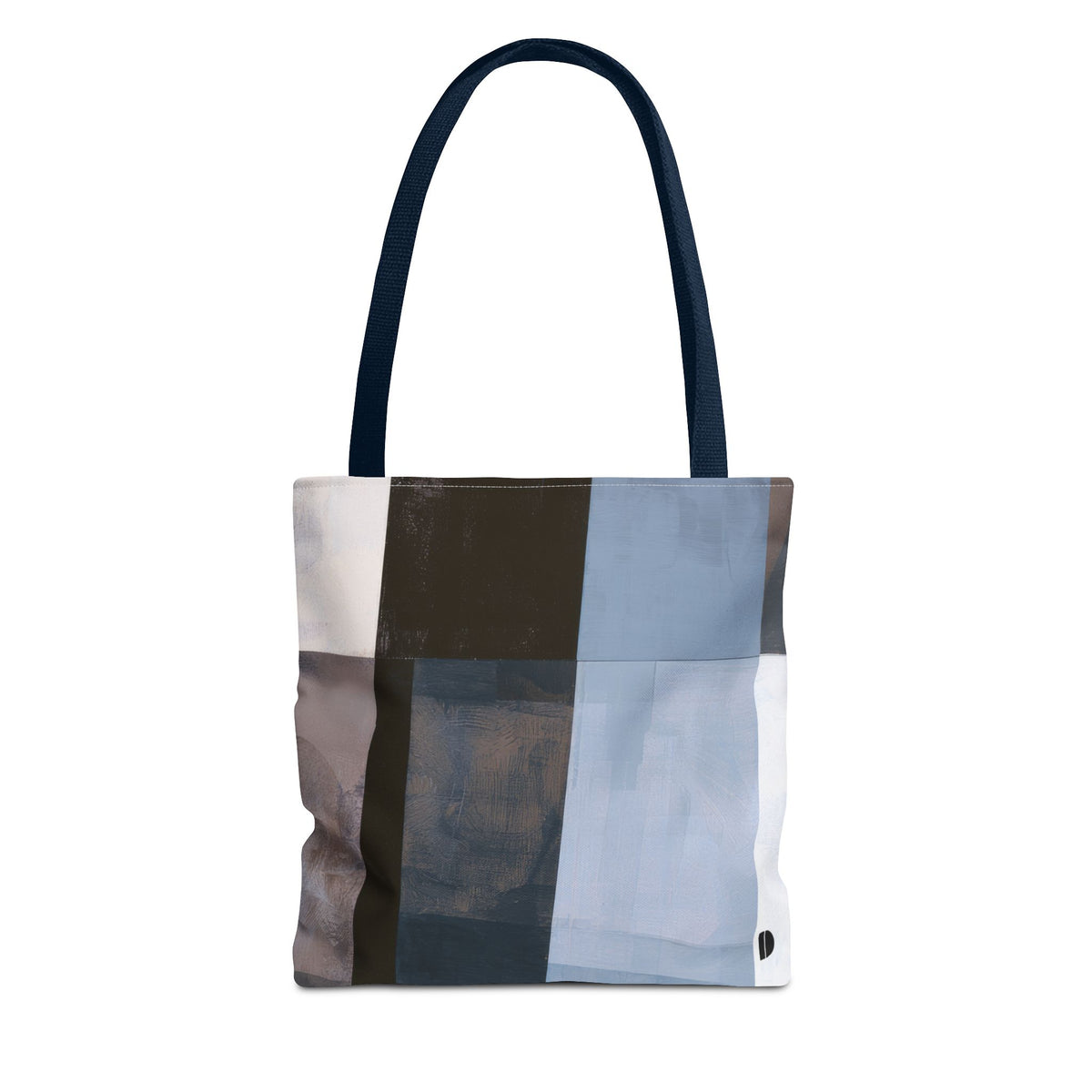 A canvas tote bag with a modern abstract patchwork design in shades of blue, brown, gray, and white, featuring dark navy blue shoulder straps, shown against a plain white background.