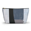 A rectangular zippered pouch with an abstract geometric patchwork pattern in shades of blue, gray, white, and charcoal, featuring a gold zipper pull and a small black logo on the bottom right.