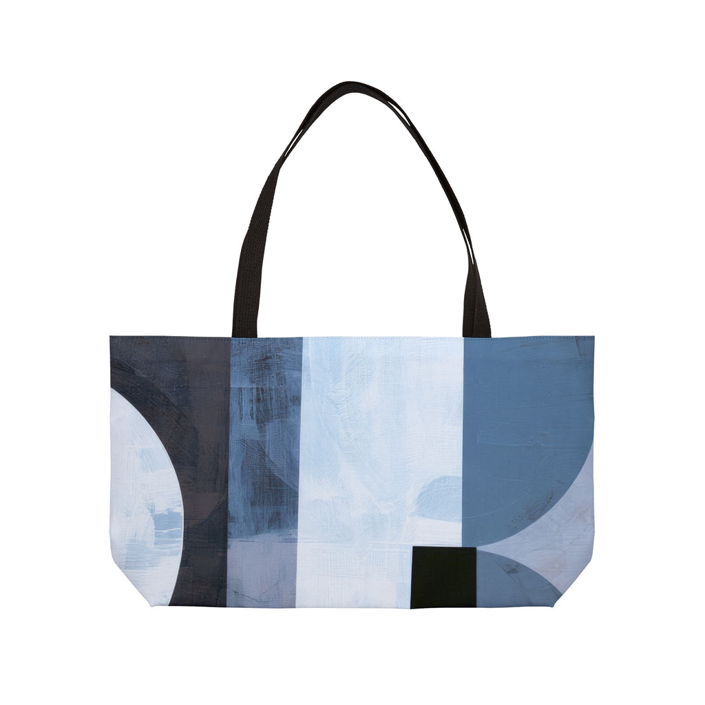 A tote bag with a modern abstract geometric print in shades of gray, blue, beige, and black, featuring two black shoulder straps, shown against a plain white background.