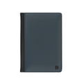 A slim, dark slate blue leather passport cover with a black side trim and a small black monogram logo in the bottom right corner, shown on a plain white background.