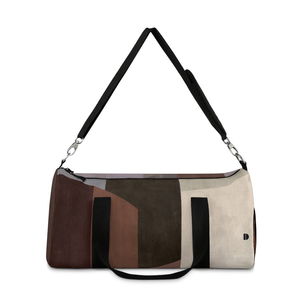 A duffle bag with an abstract geometric color-blocked pattern in brown, beige, and black, featuring a black shoulder strap and a short black carry handle, shown on a plain white background.