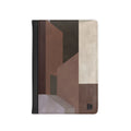 A vertical passport cover featuring an abstract geometric block pattern in shades of brown, beige, and charcoal gray. The left edge has a black stitched border, and a small black monogram logo is visible in the bottom right corner.