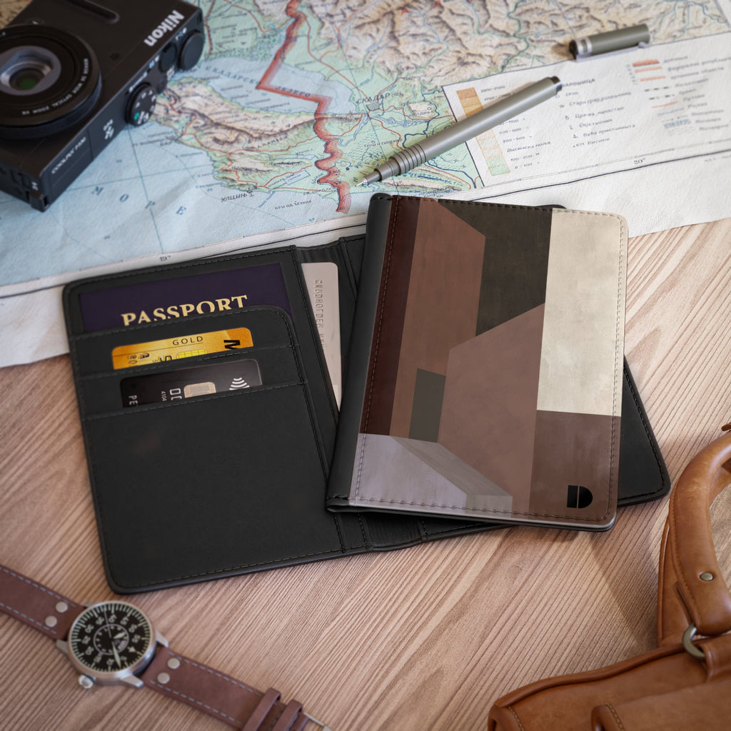 A faux leather passport holder and card case organizer shown open on a wooden surface, with a passport, cards, a map, camera, pen, watch, and leather bag around it.