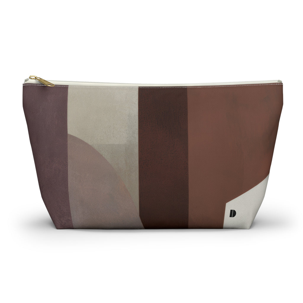 A zippered cosmetic pouch with an abstract geometric pattern in shades of brown, beige, and gray, featuring a small black 'D' logo on the bottom right corner.