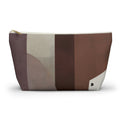 A zippered cosmetic pouch with an abstract geometric pattern in shades of brown, beige, and gray, featuring a small black 'D' logo on the bottom right corner.