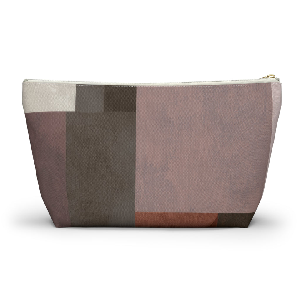 A rectangular cosmetic pouch with an abstract geometric patchwork design in muted tones of dusty rose, taupe, brown, and cream, featuring a gold zipper pull, shown on a white background.