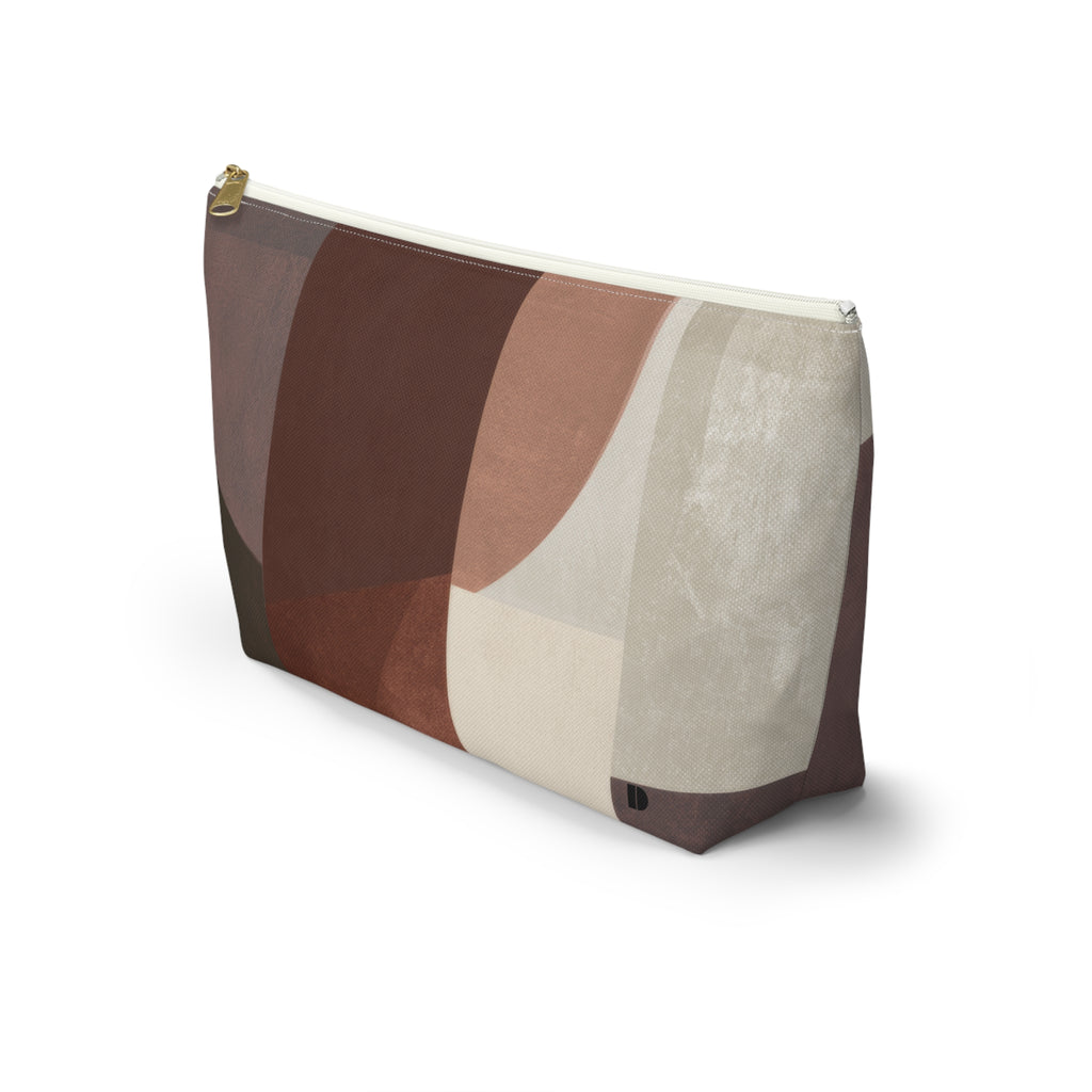 A rectangular zippered pouch with an abstract geometric pattern in shades of brown, beige, and terracotta, featuring a gold zipper pull, shown on a white background.