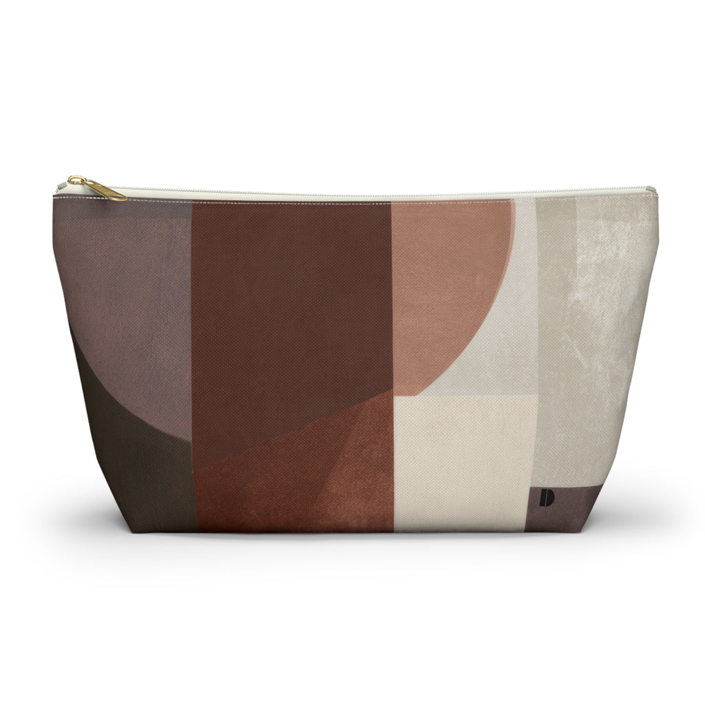 A zippered cosmetic pouch with an abstract geometric pattern in shades of brown, beige, and cream, featuring a gold zipper pull and small black logo on bottom right.