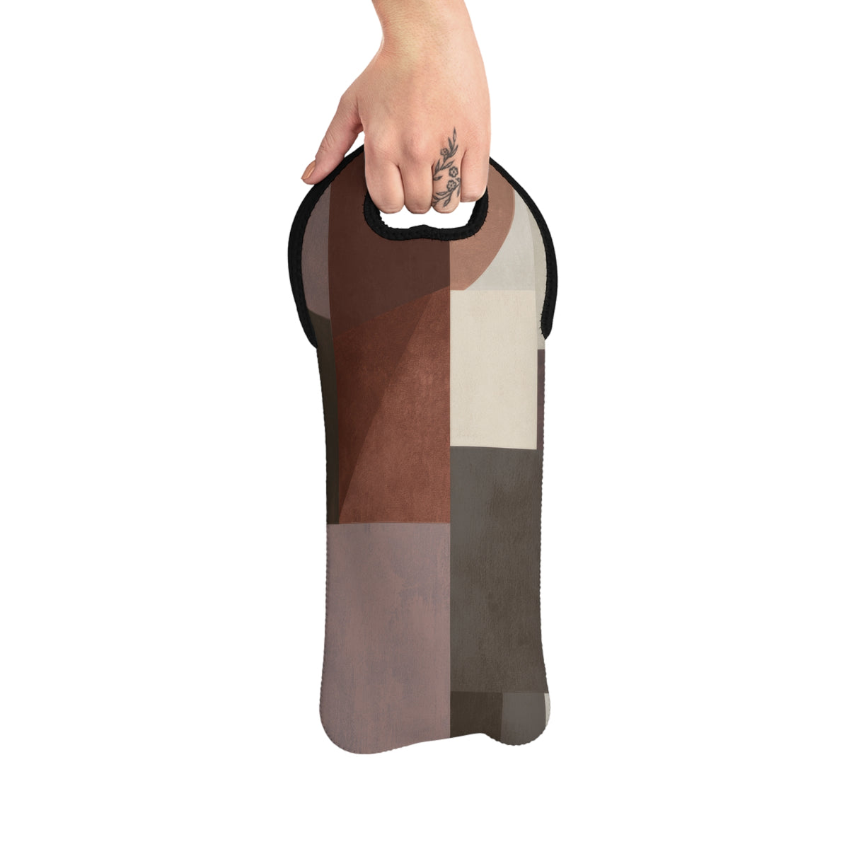 A hand holding a slim, iwine tote with a geometric patchwork pattern in brown, beige, and gray tones, set against a plain white background.