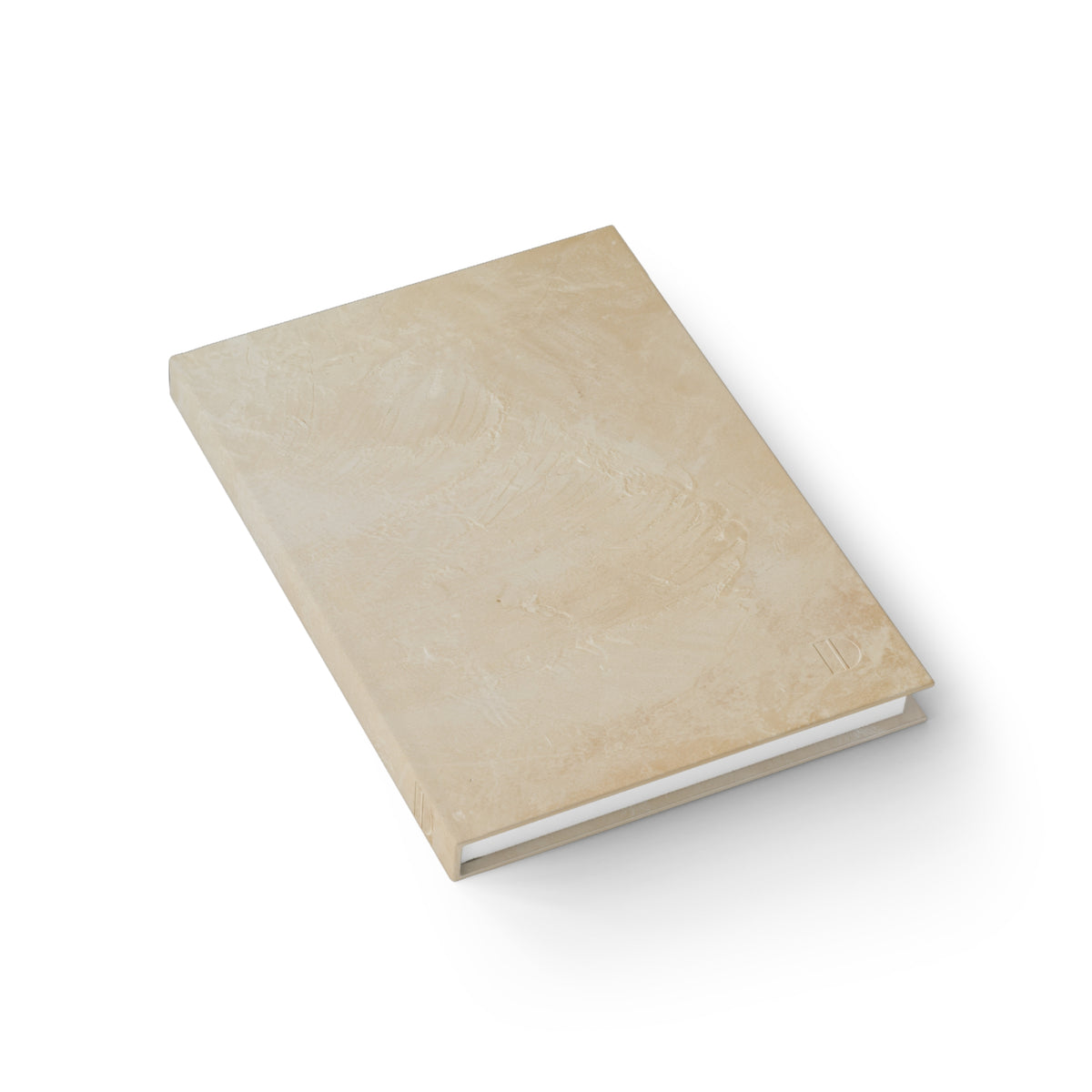 An angled overhead view of the marbled tan hardcover journal by The Cultivated Desk, showcasing the sturdy spine construction and high-quality paper book block.
