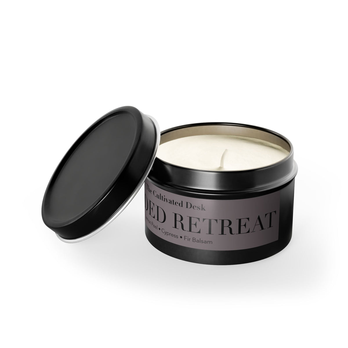 An open black metal tin candle with cream-colored soy wax, shown on a clean white background. The label reads 'The Cultivated Desk' and 'WOODED RETREAT'.