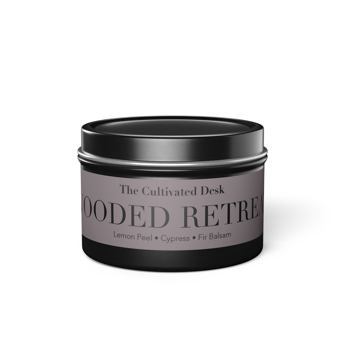 A round black metal tin candle jar with a muted taupe-gray label reading 'The Cultivated Desk' and 'WOODED RETIREAT' with scent notes 'Lemon Peel • Cypress • Fir Balsam' on a white background.